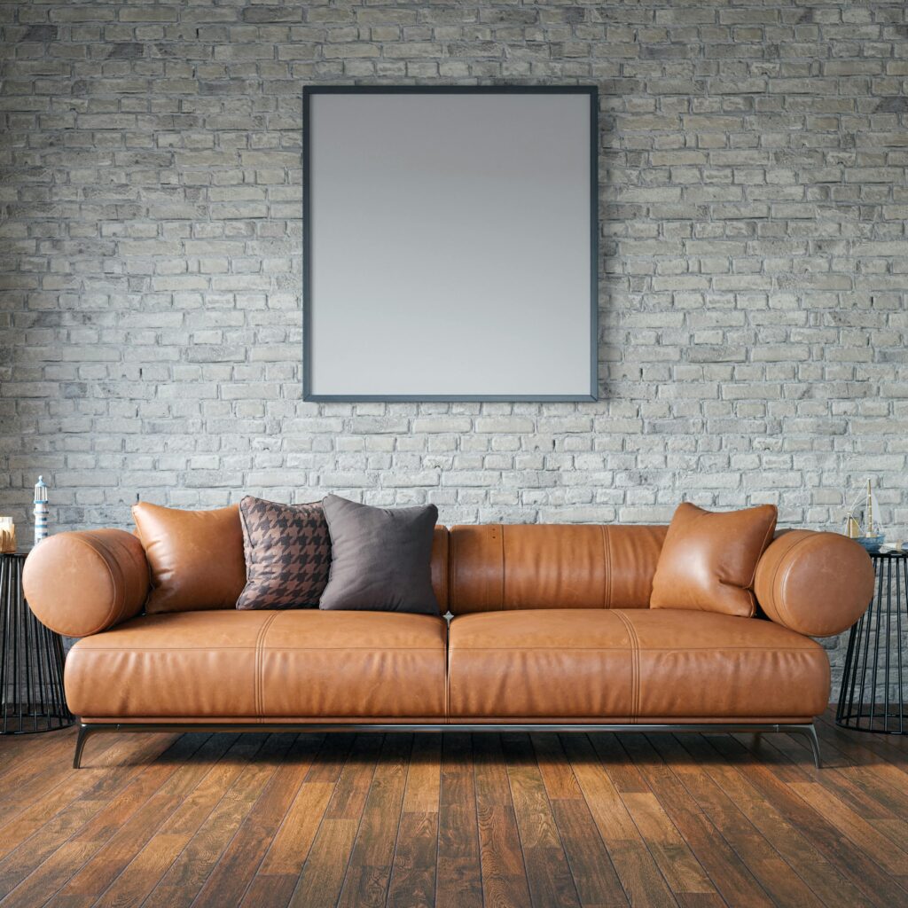 A modern leather sofa against a brick wall in an elegant living room with wooden flooring.
